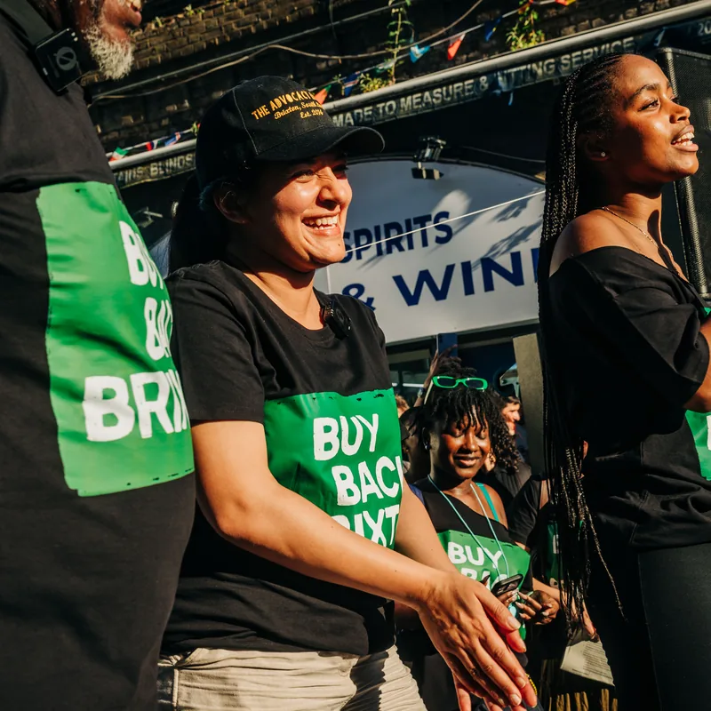 Two women on stage sharing a microphone as they speak to the rally.