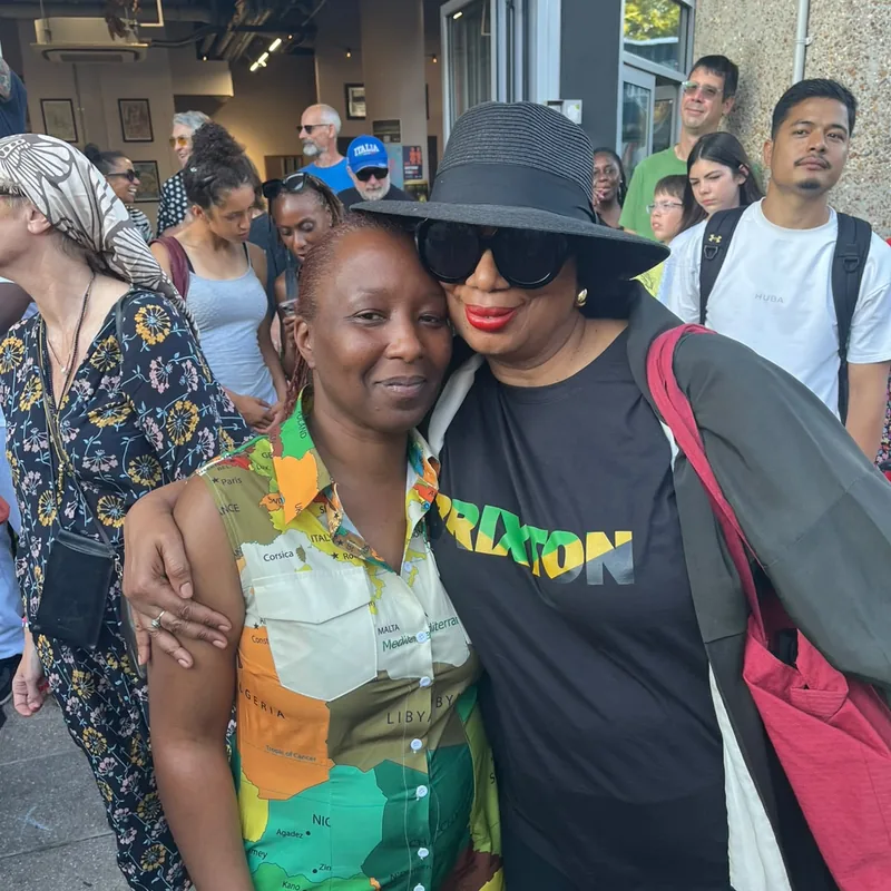 Two women arm in arm at the rally, one in a Brixton T-shirt.